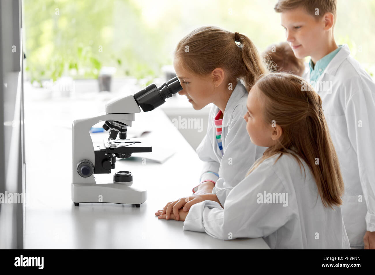 I ragazzi o studenti di biologia microscopio a scuola Foto Stock