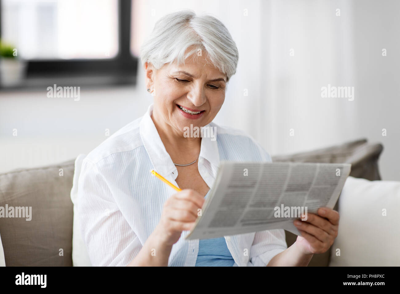 Senior marcatura donna giornale di annunci a casa Foto Stock