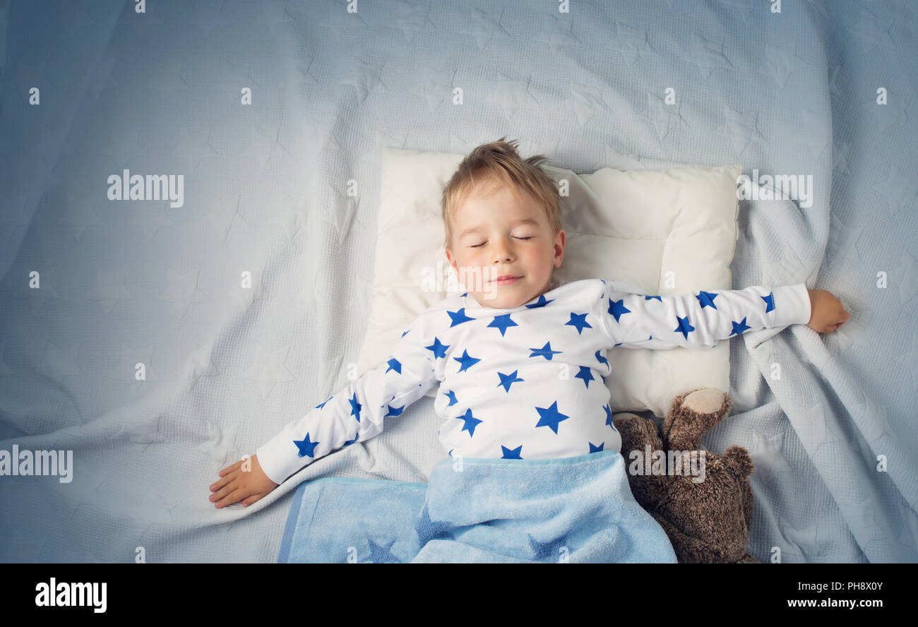 Sei anni bambino che dorme nel letto con la sveglia Foto stock - Alamy