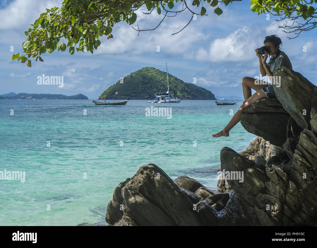 Donna seduta sulla roccia con fotocamera facendo le foto Foto Stock