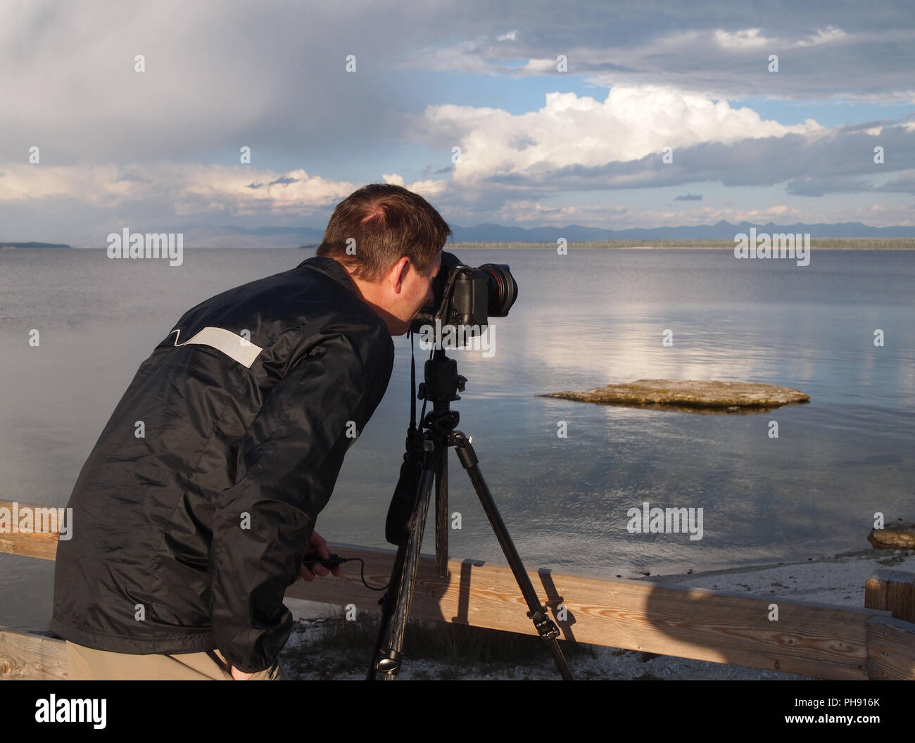 L'uomo prendendo foto del lago con la telecamera montata su treppiede Foto Stock