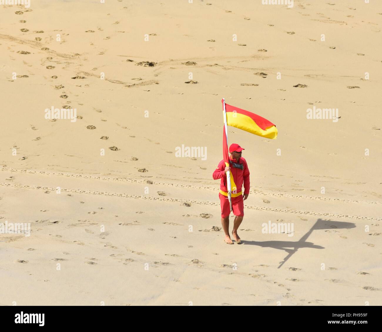 RNLI bagnino di turno che porta un rosso e bandiera gialla in tutta la spiaggia,Riviere Towans beach, Phillack, Hayle,cornwall,l'Inghilterra,UK Foto Stock