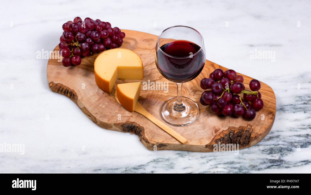 Vino rosso con formaggio gourmet e Uva su server in legno Foto Stock