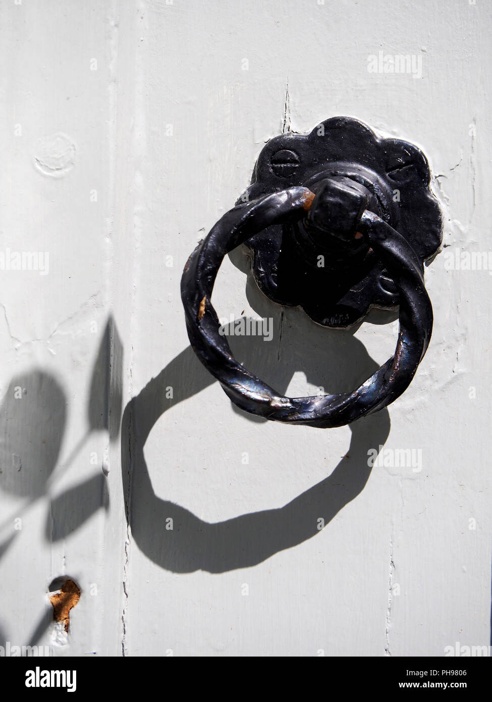 Una ghisa ghiera decorativa della maniglia della porta e sul vecchio dipinto di bianco porta in legno. Foto Stock
