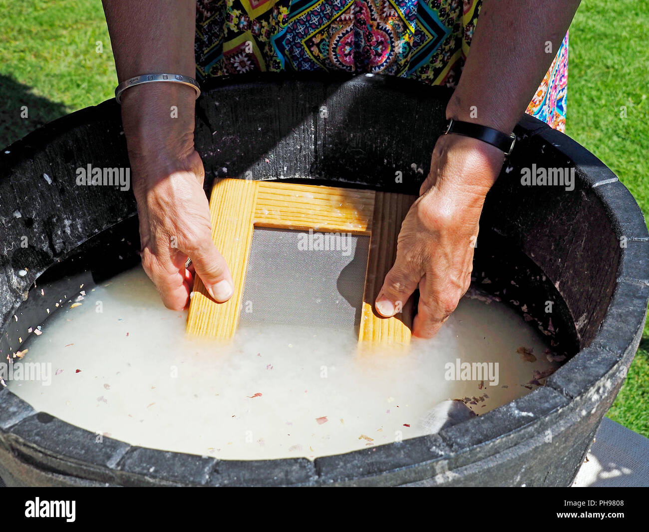 Una dimostrazione di semplice produzione di carta. Immersione del telaio o deckle nella pasta. Foto Stock