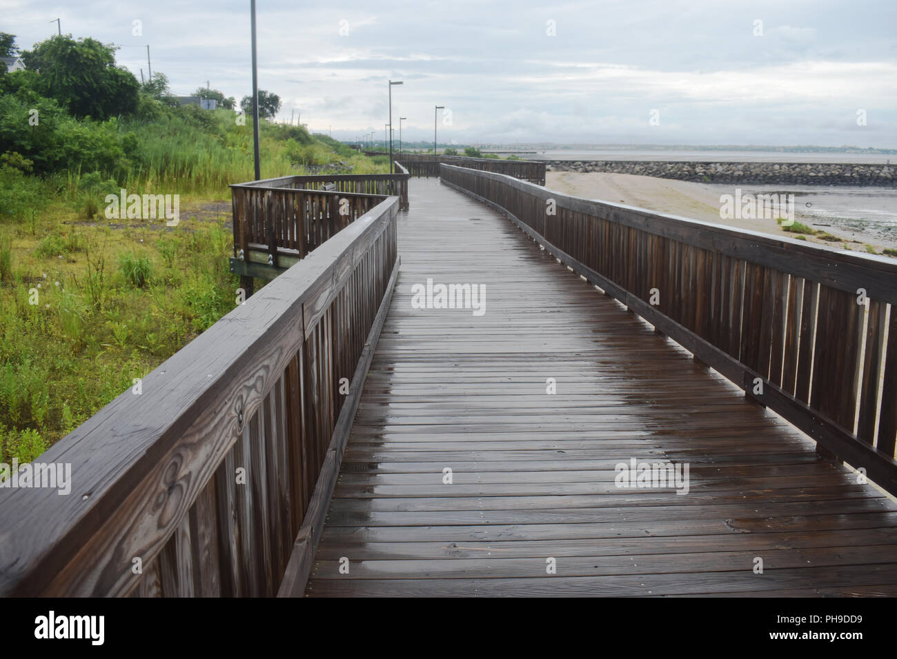 Wet boardwalk dopo una pioggia di estate di tempesta in spiaggia locale Foto Stock