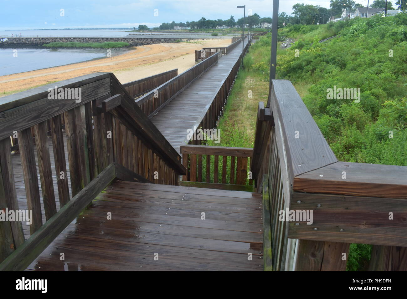 Wet boardwalk dopo una pioggia di estate di tempesta in spiaggia locale Foto Stock