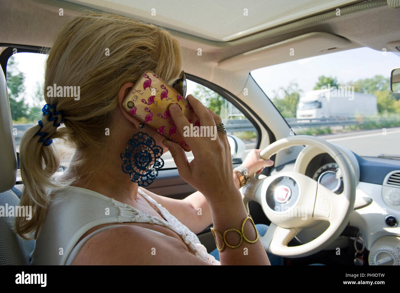 BOTTROP, Germania - 16 agosto 2018: una donna bionda sta chiamando con il suo smartphone mentre si guida su una strada in piena velocità. Foto Stock