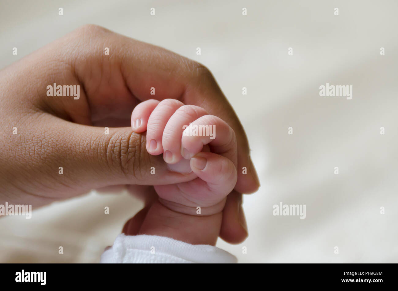 Baby mano tenendo un dito di donna Foto Stock