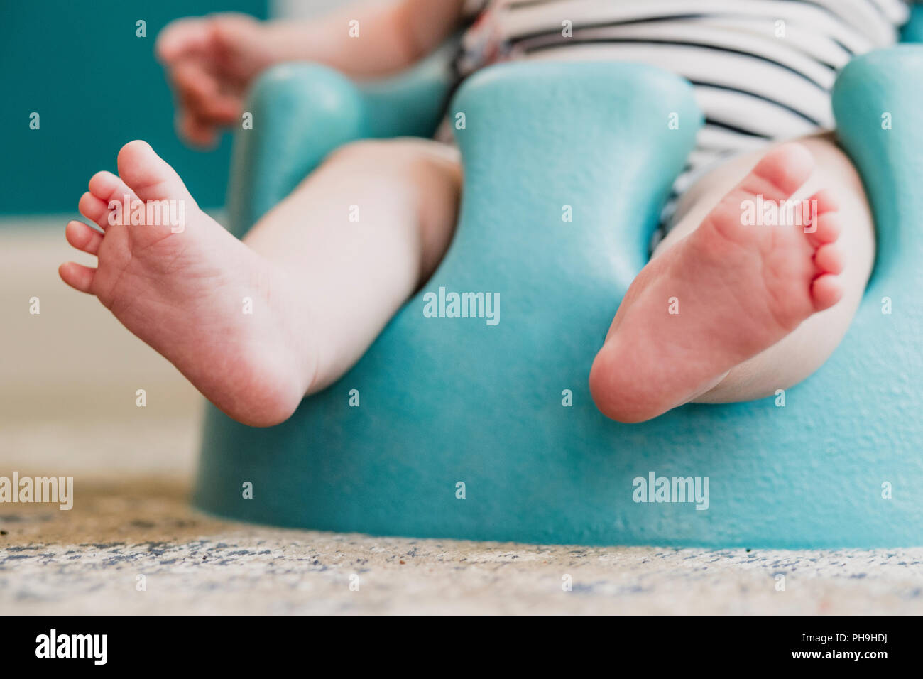 Basso angolo vista frontale di un irriconoscibile baby. Il bambino è seduto in un piano sedile, il focus è il bebè piedi. Foto Stock