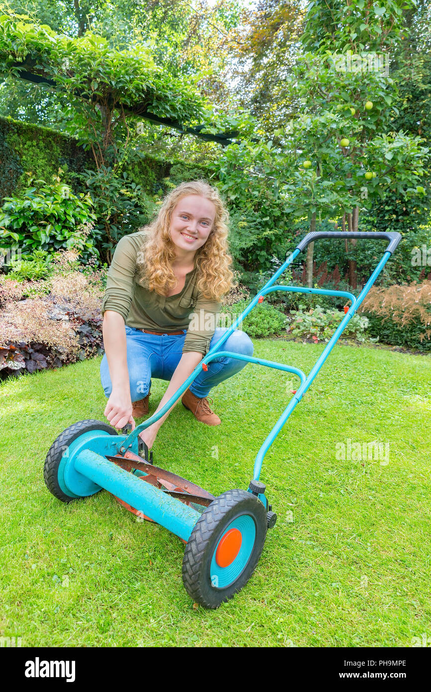 Giovane donna olandese riparazioni tosaerba in giardino Foto Stock