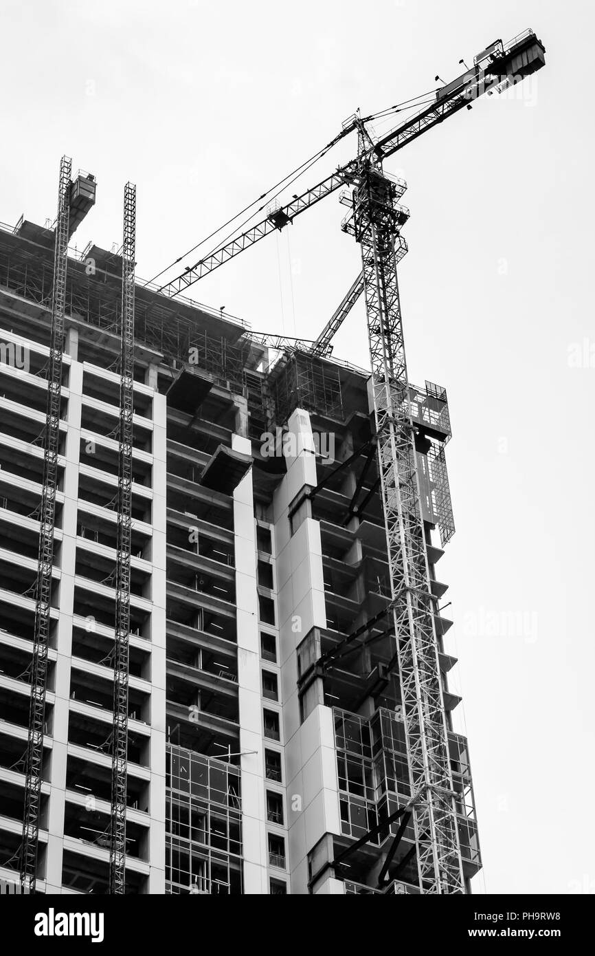 La costruzione di un edificio alto che nel processo di sviluppo e di una torre della gru sul suo lato. Foto Stock