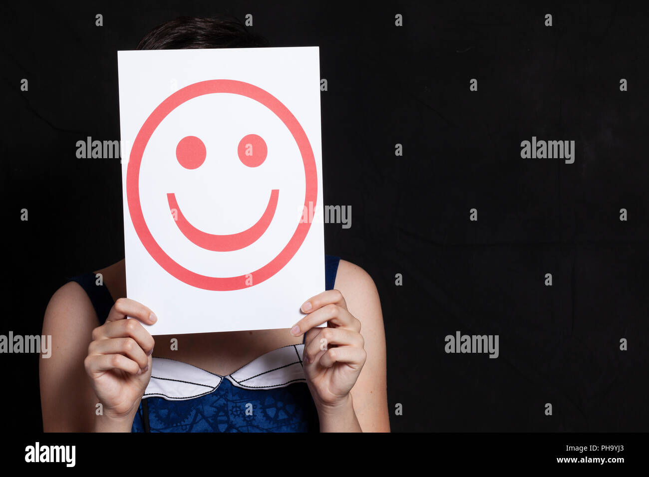 Donna che mantiene il sorriso di emoticon Foto Stock