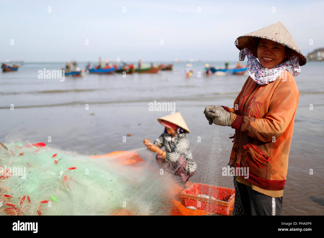 I pescatori e le donne la riparazione di reti da pesca a Tam Duong beach, Vung Tau, Vietnam, Indocina, Asia sud-orientale, Asia Foto Stock
