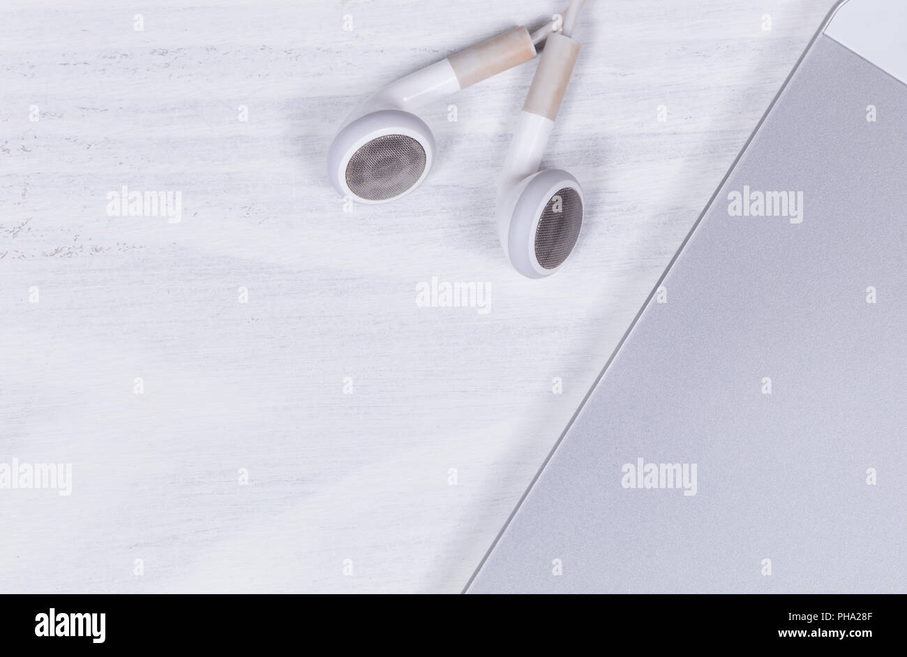 Telefono cellulare e auricolari sul bianco pulito lo sfondo del desktop Foto Stock