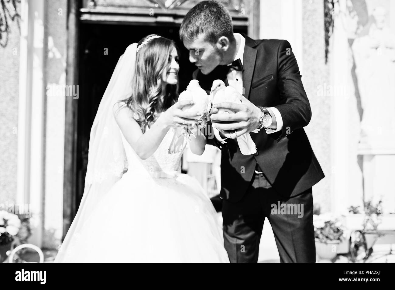 Happy sposi con le colombe a portata di mano la chiesa di sfondo Foto Stock