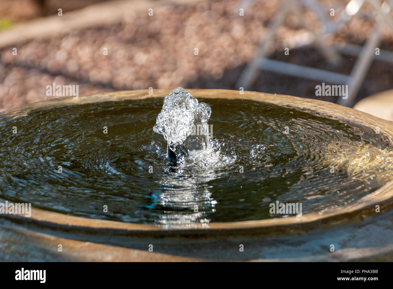 Acqua limpida che viene spinto fuori dalla parte superiore del calcestruzzo di una fontana di acqua Foto Stock
