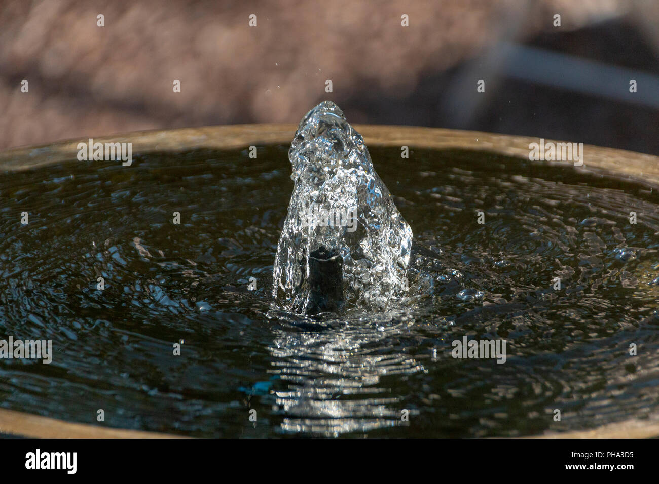 Acqua limpida che viene spinto fuori dalla parte superiore del calcestruzzo di una fontana di acqua Foto Stock