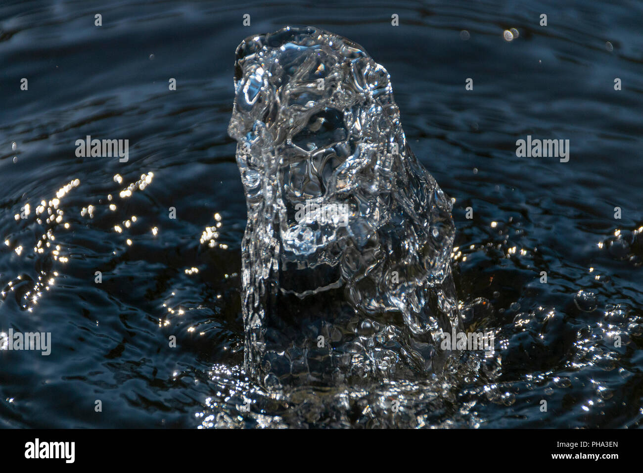 Una vista ravvicinata di acqua limpida che viene spinto fuori dalla parte superiore del calcestruzzo di una fontana di acqua Foto Stock