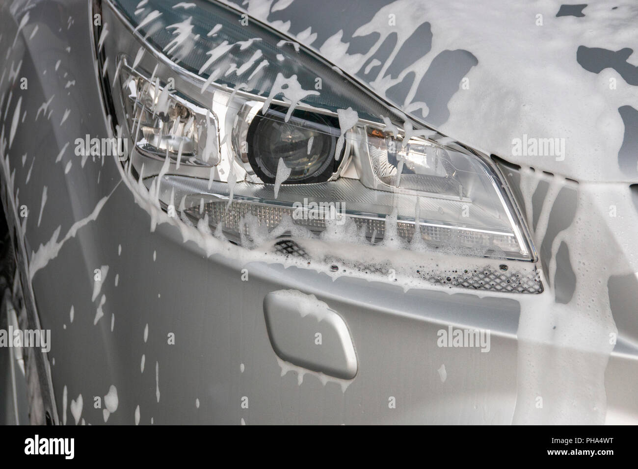 Una chiusura di schiuma di sapone sul lato sinistro della luce principale di un nastro in auto Foto Stock