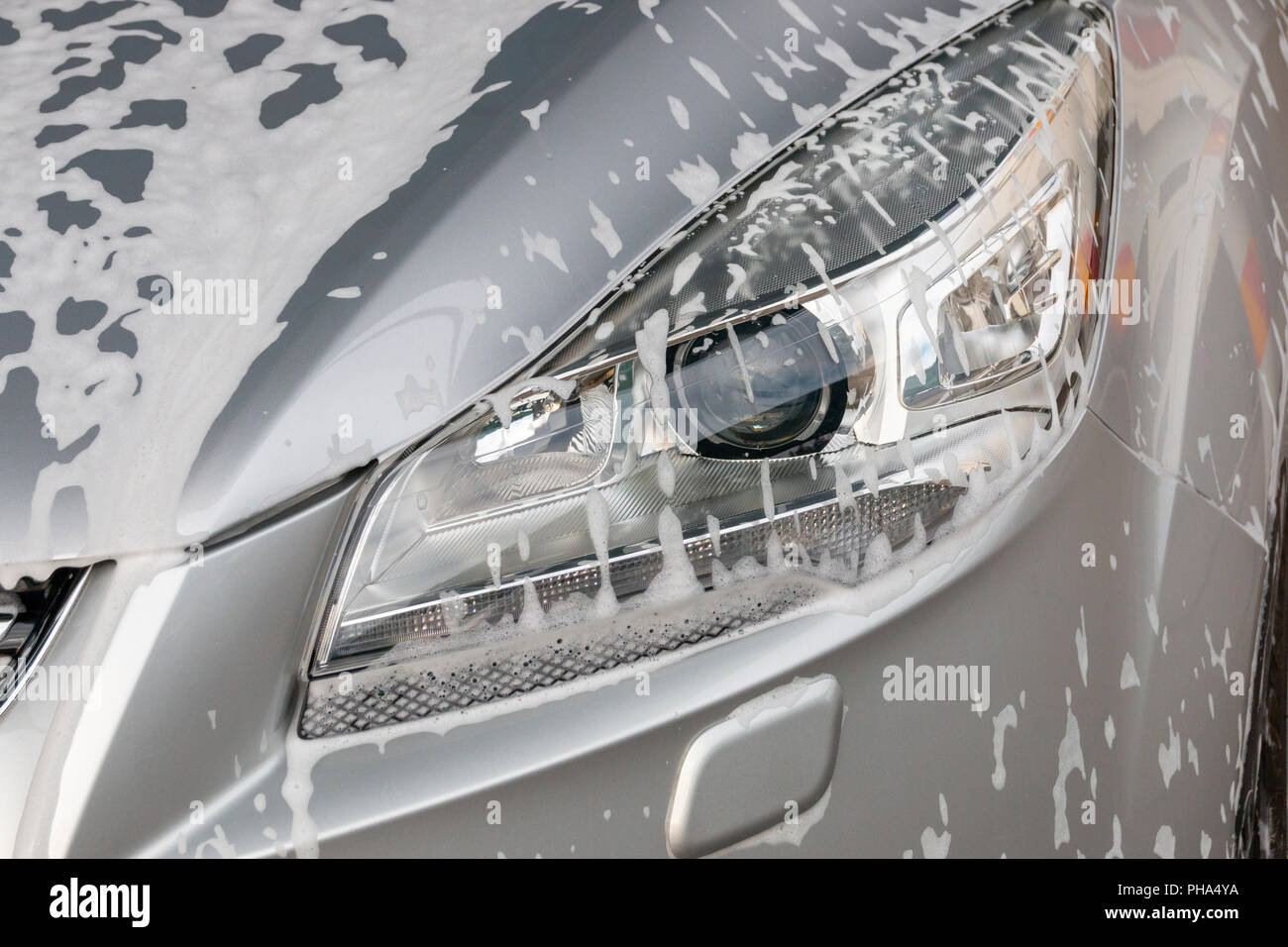 Una chiusura di schiuma di sapone sul lato destro della luce principale di un nastro in auto Foto Stock