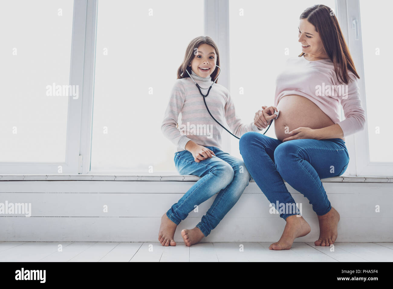 Donna incinta con sua figlia entusiasta Foto Stock