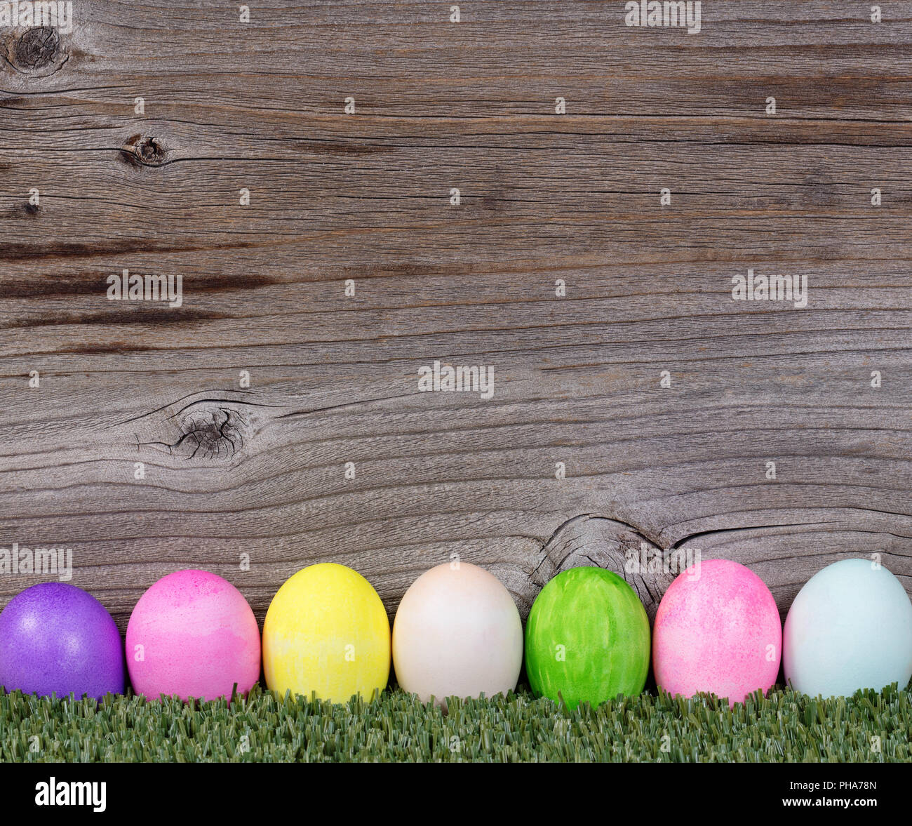 Colorate le uova di Pasqua in appoggio su erba rustico con sfondo di legno Foto Stock