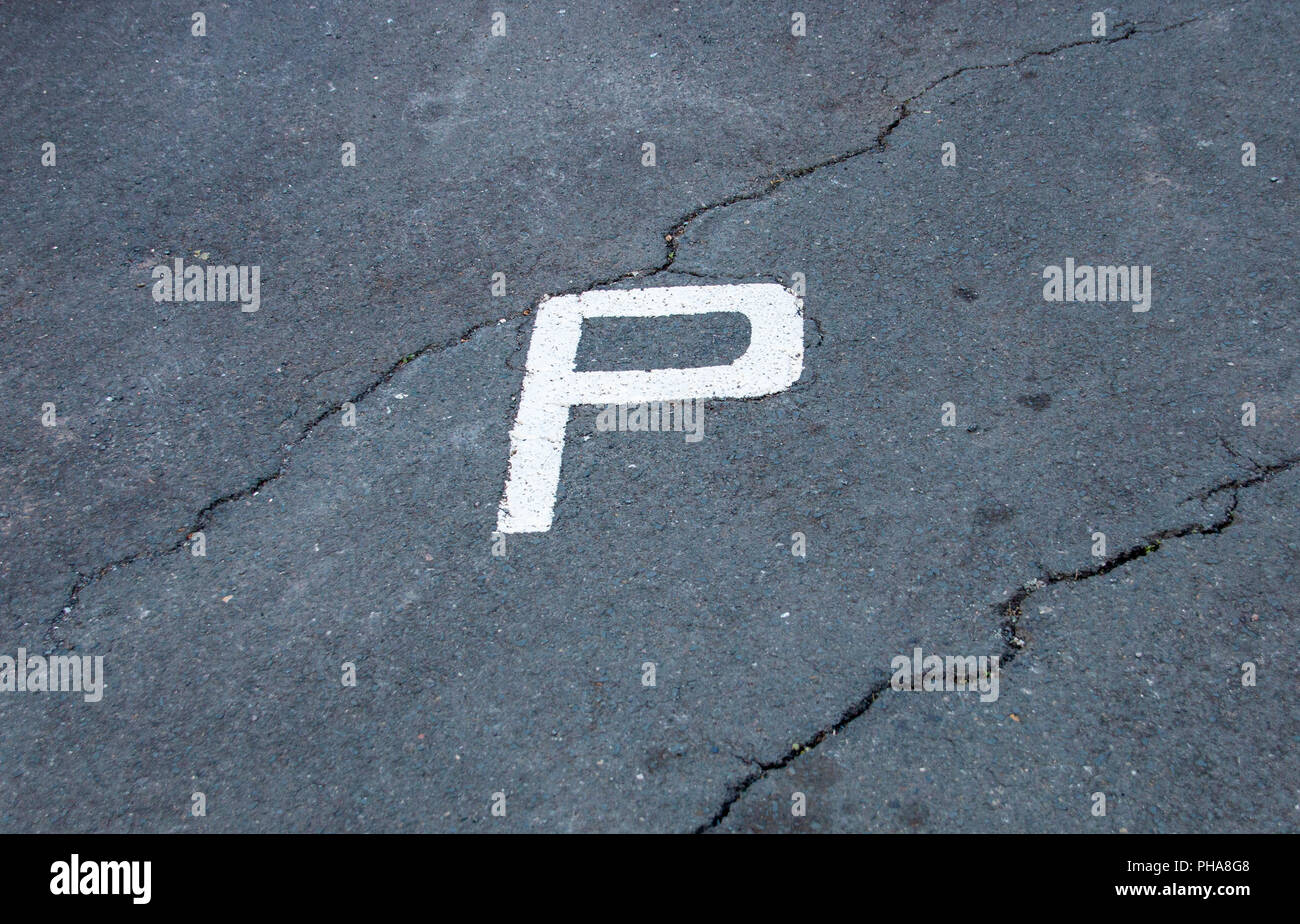 Una vista in pianta di un dipinto di bianco P delimitante una zona di parcheggio su asfalto rotto Foto Stock