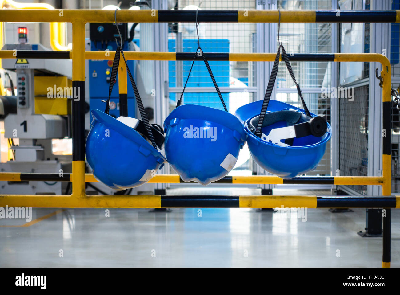 Fabbrica di caschi industriale appeso al minimo di sicurezza in attesa Foto Stock