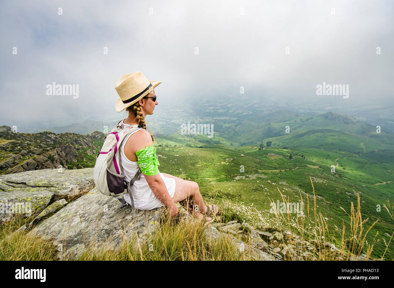 Concetto di viaggio: giovane turista ragazza con uno zaino seduto sul bordo di una scogliera. Copia dello spazio. Foto Stock