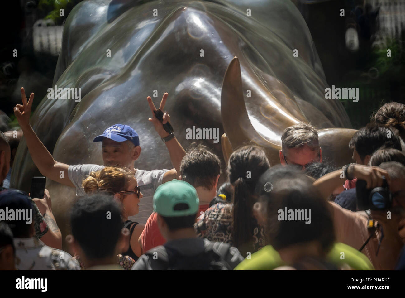 Orde di turisti cluster intorno e posare per le foto di fronte al Wall Street Bull, artista Arturo DiModica, su Broadway in Lower Manhattan a New York il giovedì 30 agosto, 2018. Il mercato azionario è avente la più lunga bull run nella storia, a partire dal 9 marzo 2009 come la grande recessione si è conclusa. (Â© Richard B. Levine) Foto Stock