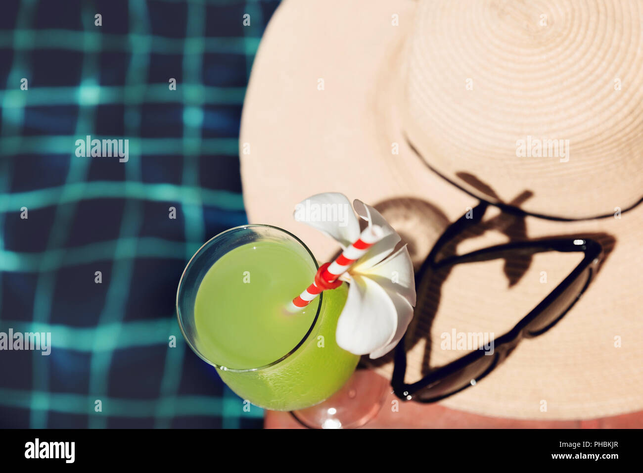 Freschi Succhi di guaiava drink con fiore, occhiali da sole e cappello di paglia sul bordo di una piscina - vacanza concetto tropicale Foto Stock