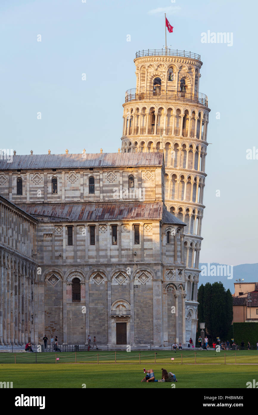Persone rilassante sui prati del Campo dei Miracoli con la cattedrale e la Torre Pendente dietro, Sito Patrimonio Mondiale dell'UNESCO, Pisa, Toscana, Italia Foto Stock