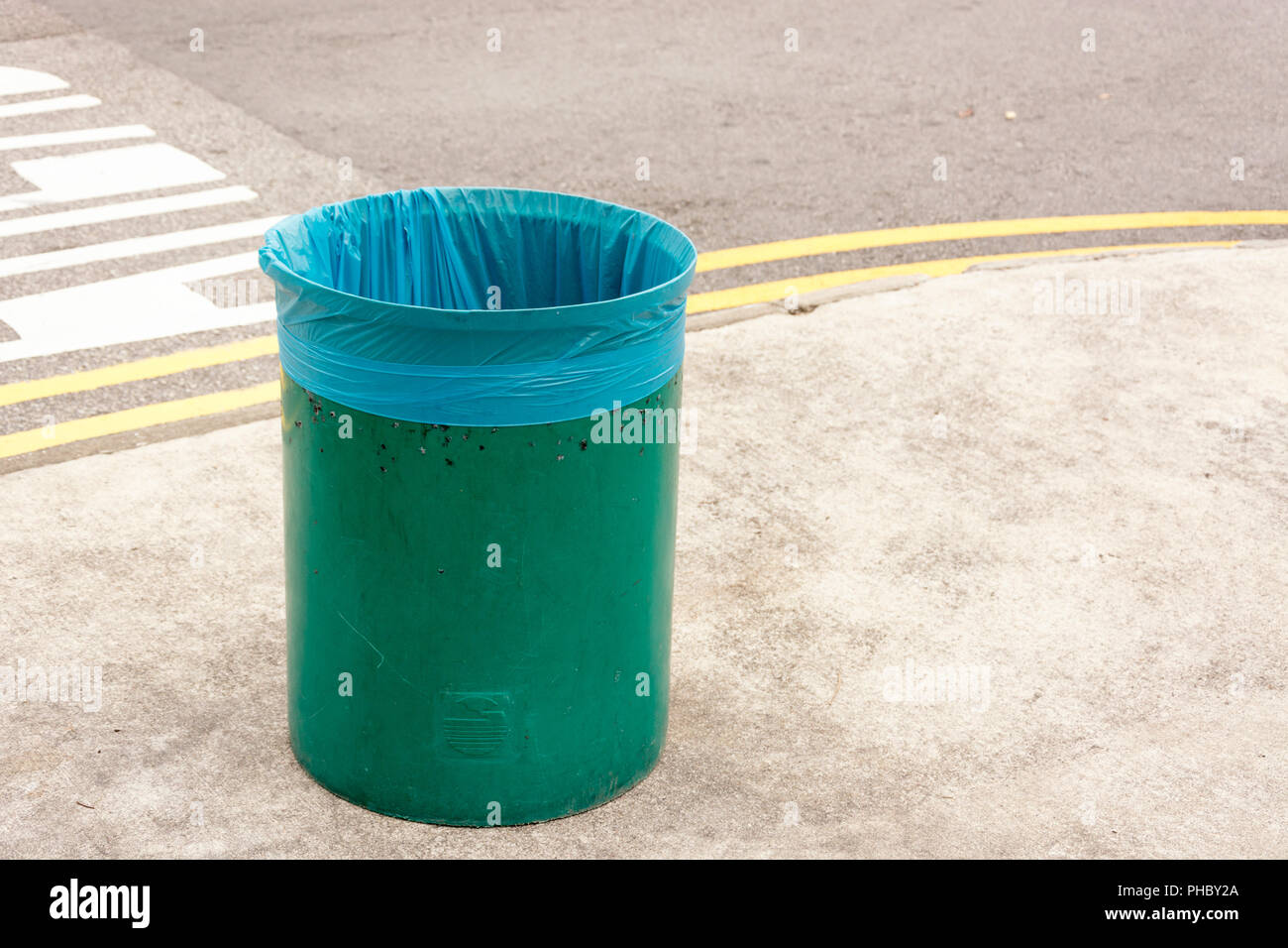 Unico verde vuoto contenitore di rifiuti con nuove e pulite blu sacchetto di plastica nell'area pubblica. Destinata a mantenere l'ambiente pulito, ordinato e pulito. Foto Stock