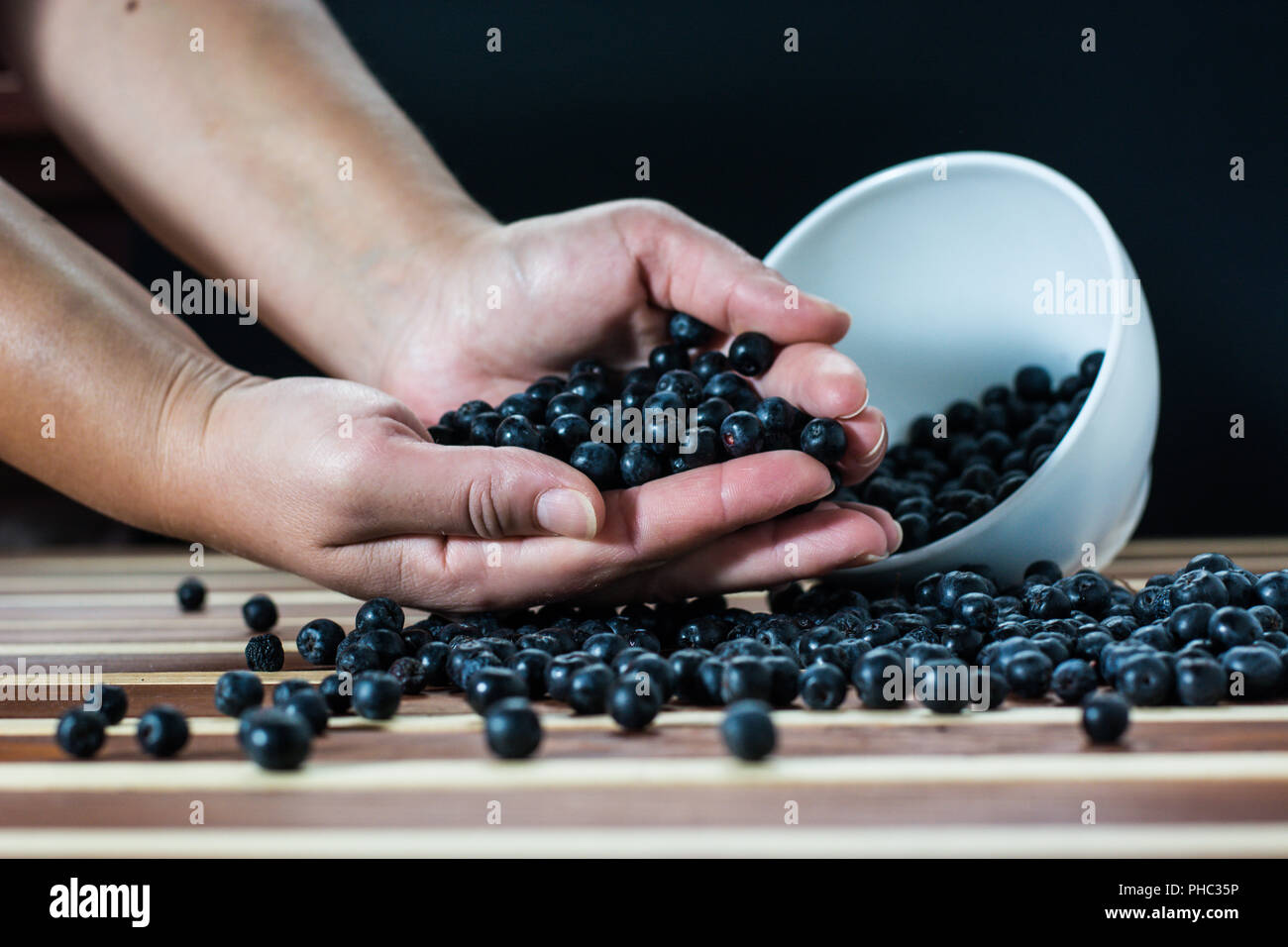 Mani femminili con aronia sul tavolo Foto Stock Mani femminili con aronia sul tavolo Foto Stock