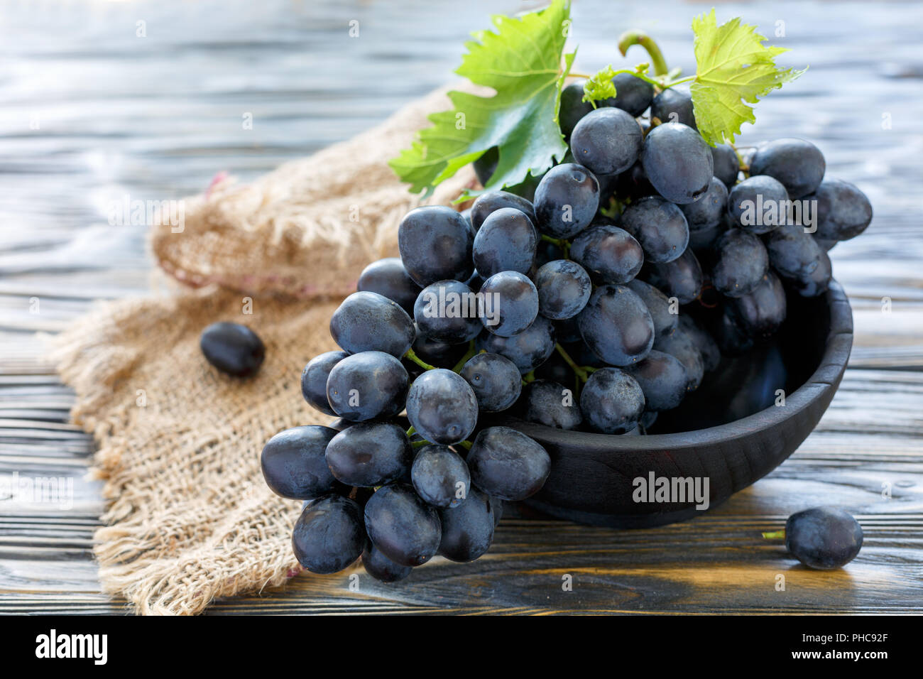 Deliziosa uva nera in una ciotola di legno. Foto Stock