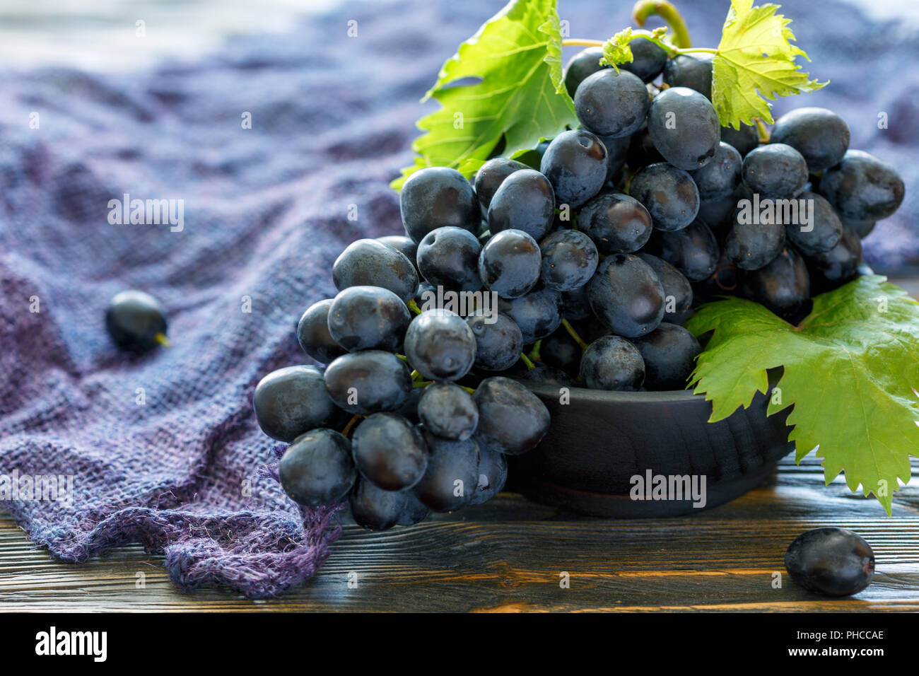 Mature di uva nera in una ciotola di legno. Foto Stock