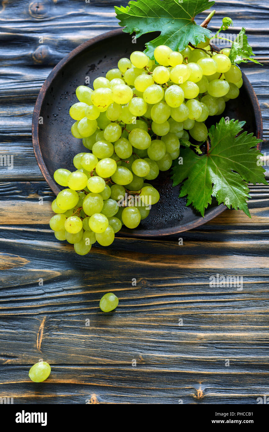 Grappolo di uva bianca su un tagliere di legno. Foto Stock