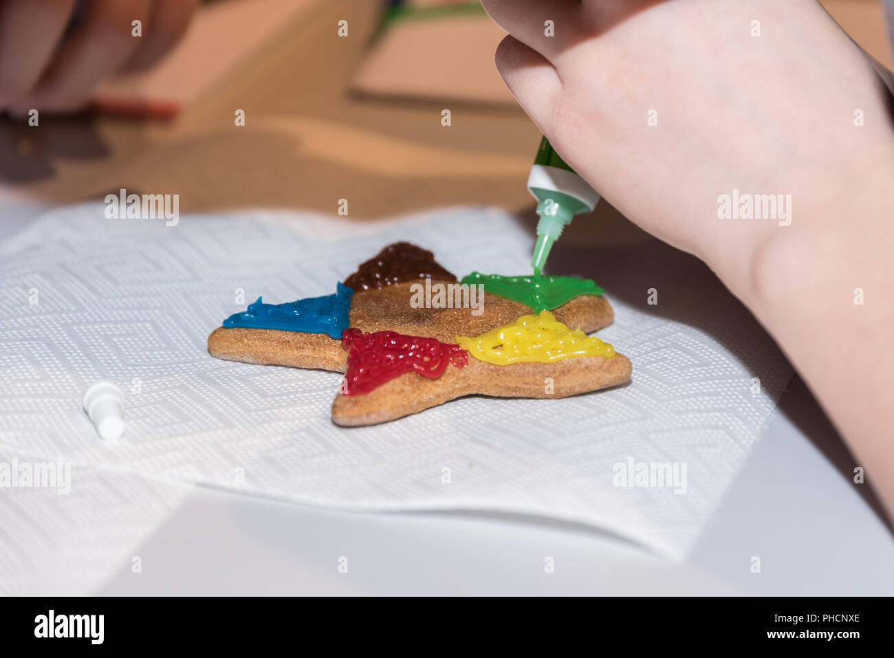 Persona decora gingerbread stella con glassa colorata - close-up Foto Stock