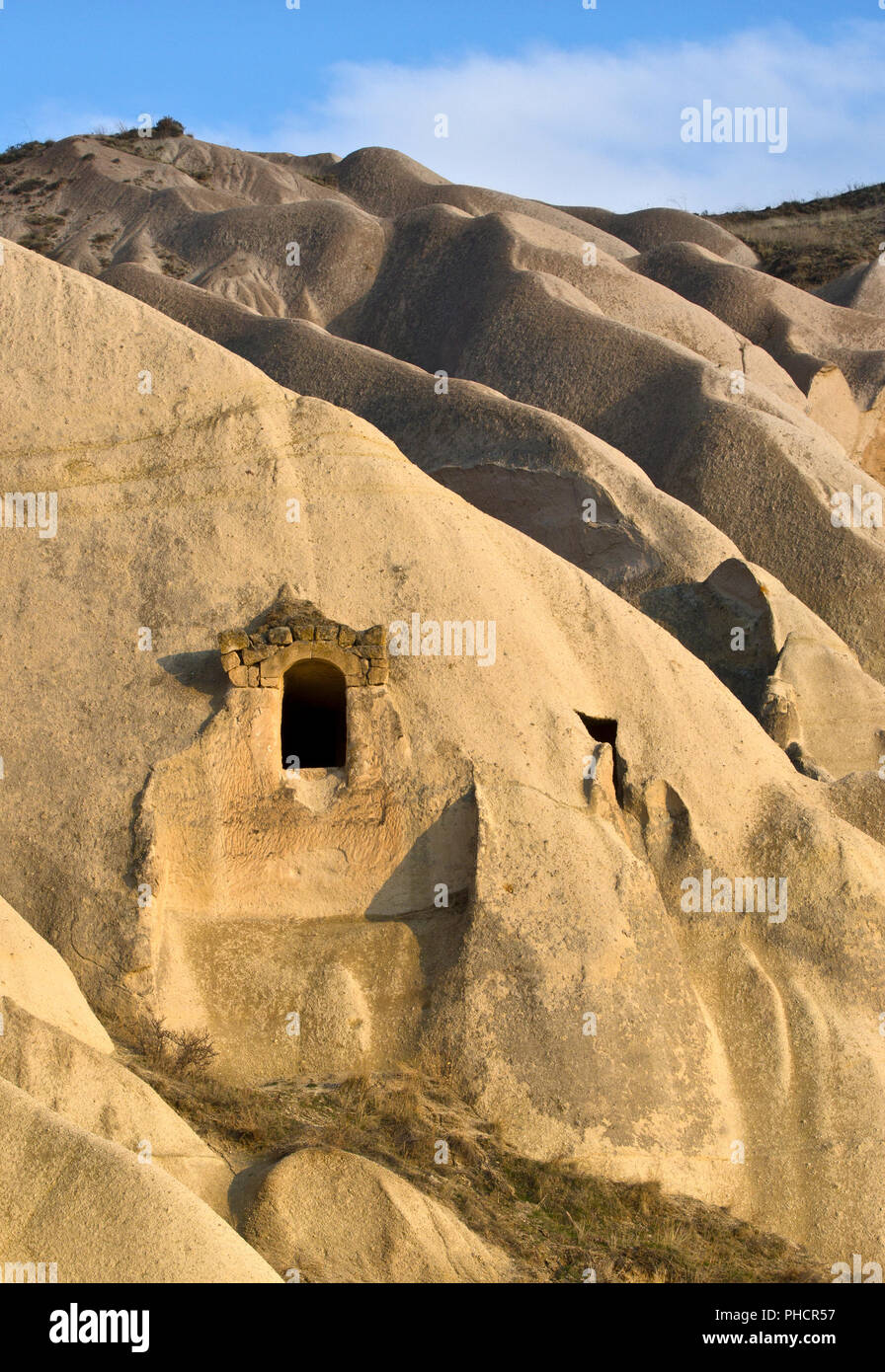 Antica dimora costruito sul fianco di una collina nella valle delle rose, Cappadocia, Turchia Foto Stock