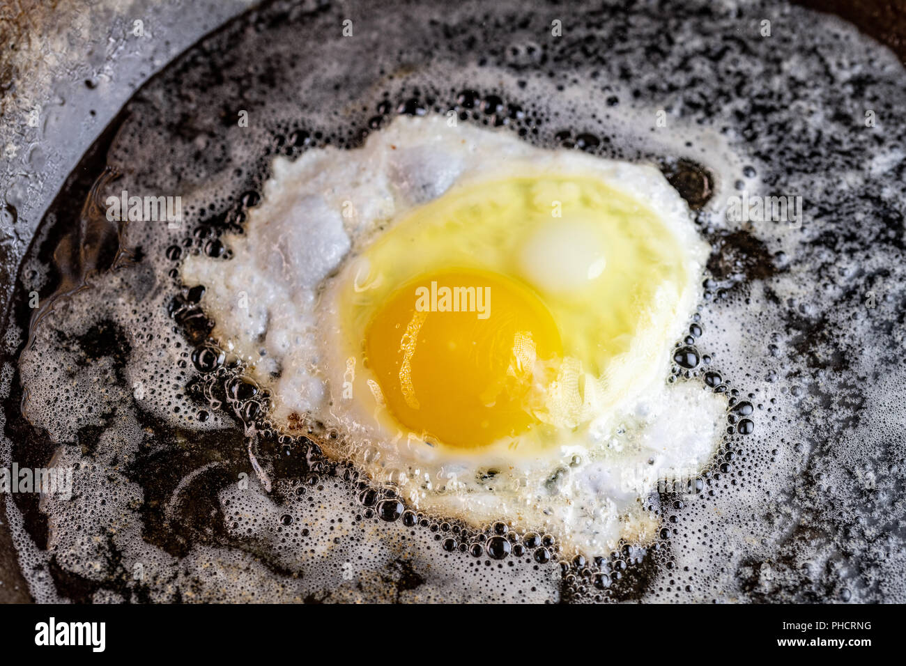 Un uovo frittura in olio e burro in un acciaio al carbonio padella Foto Stock