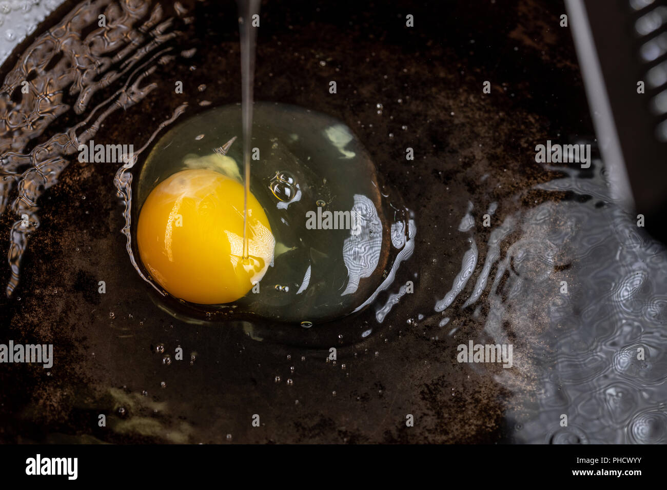Un uovo frittura in olio e burro in un acciaio al carbonio padella Foto Stock