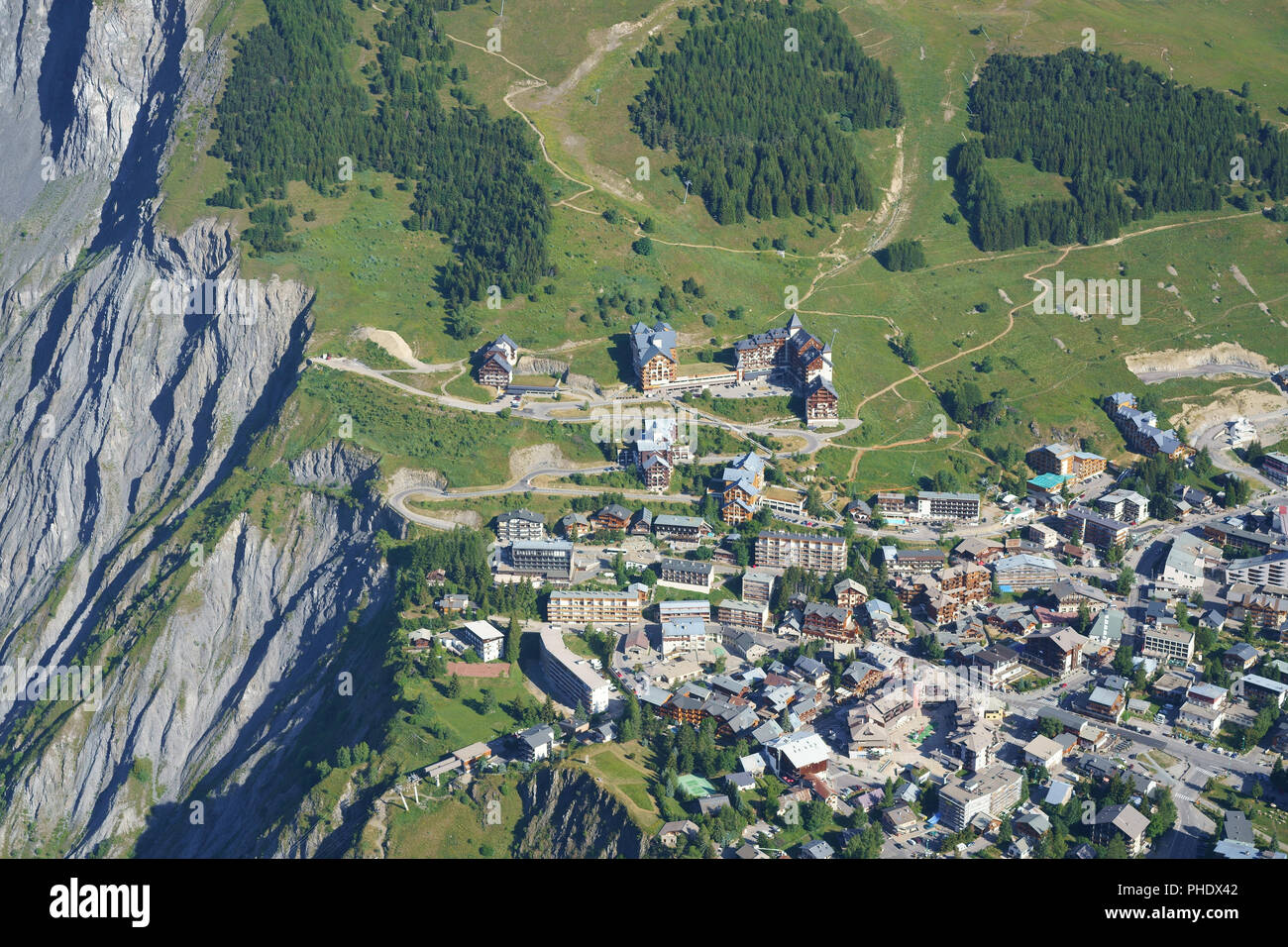 VISTA AEREA. Headward Erosion, troppo vicino per il comfort, al limite della città. Stazione sciistica di Les Deux Alpes in estate. Isère, Auvergne-Rhône-Alpes, Francia Foto Stock