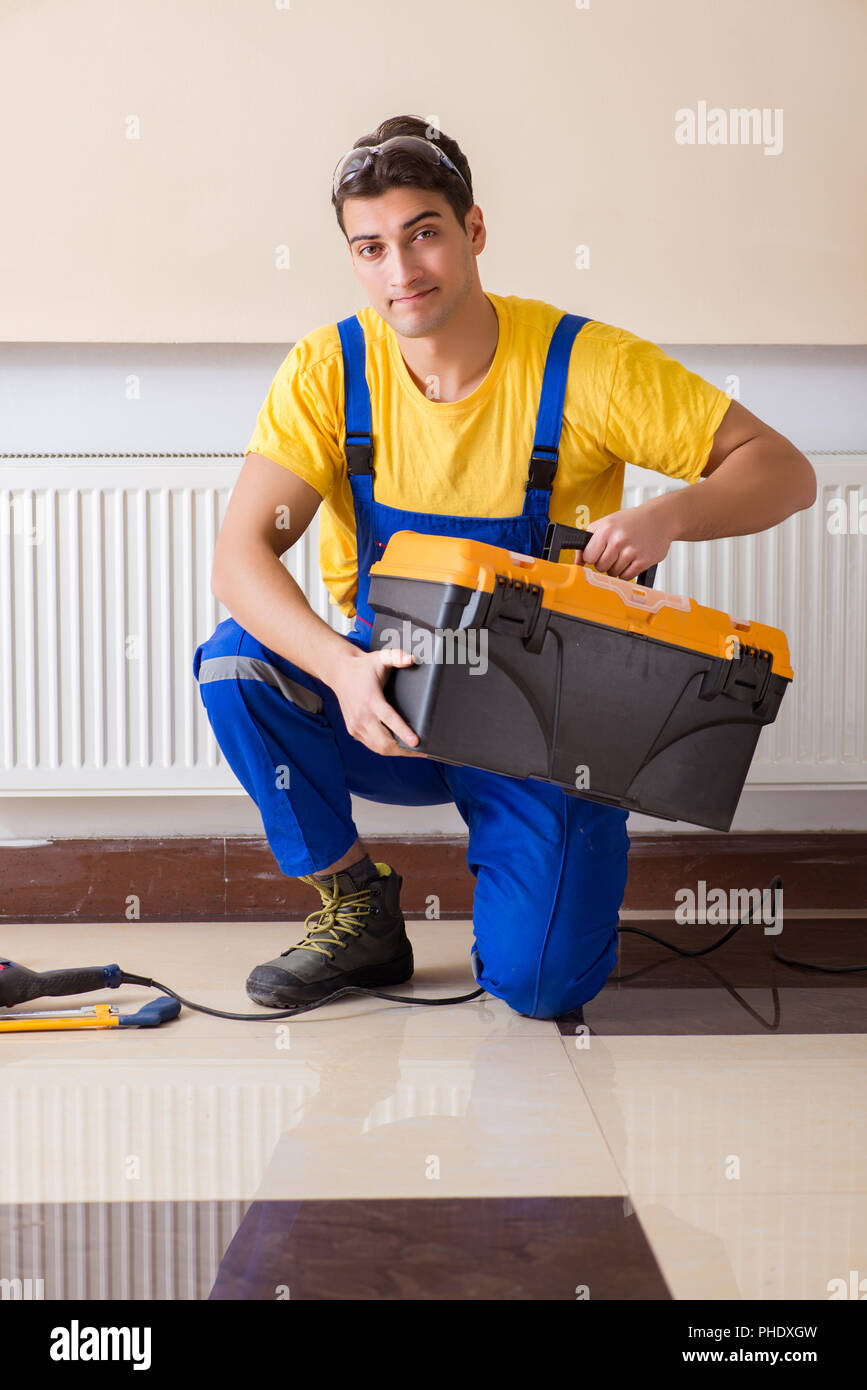 Giovani repairman contraente la riparazione del pannello di riscaldamento Foto Stock