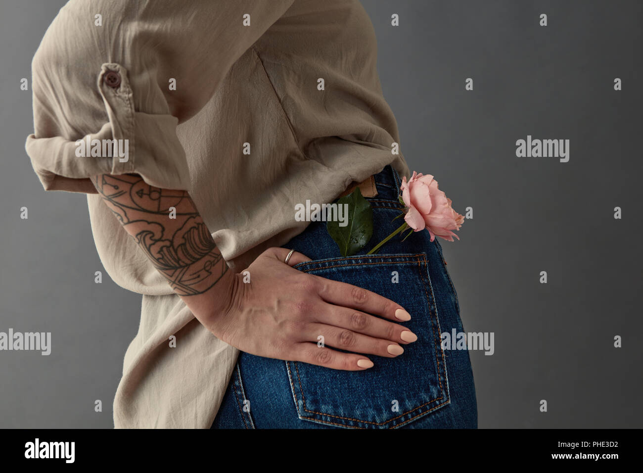 Una ragazza in jeans blu con una rosa rosa Foto Stock