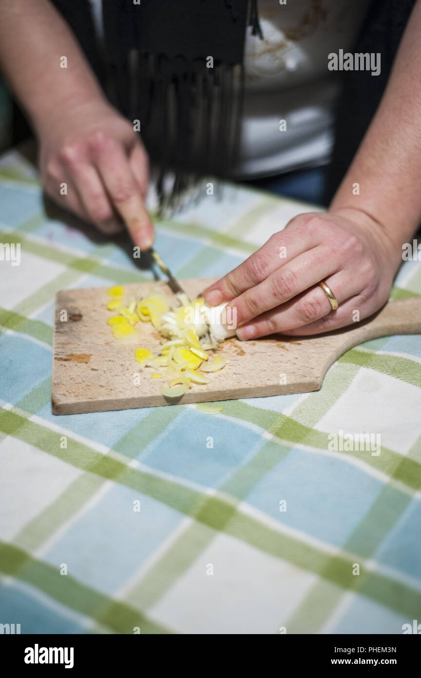 Donna con le mani in mano tagliare le verdure sul tagliere Foto Stock