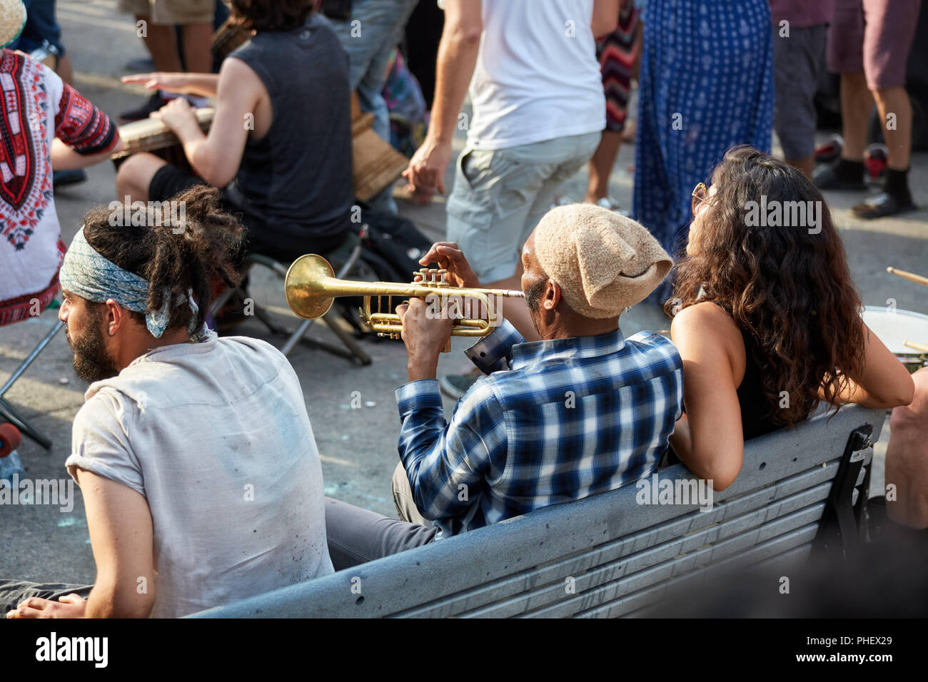 Montreal, Canada - Giugno, 2018. African American maschio seduta su una panchina e soffiaggio di tromba al Tam Tam festival di Mount Royal Park, Montreal, Canada Foto Stock