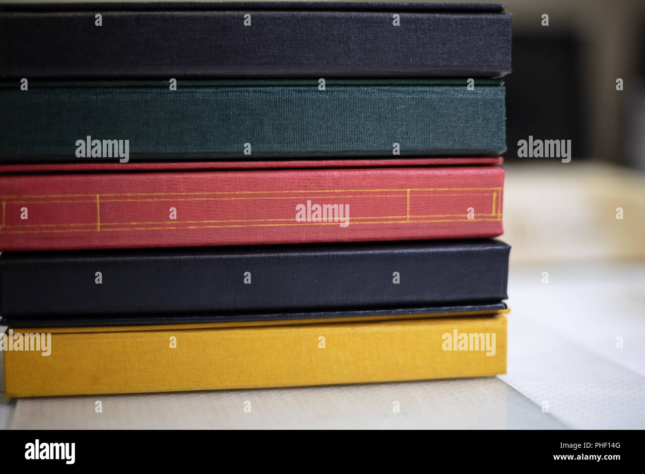 Spine di una pila di libri in colori assortiti e con texture binding personalizzati a un libro legante in una vista ravvicinata Foto Stock