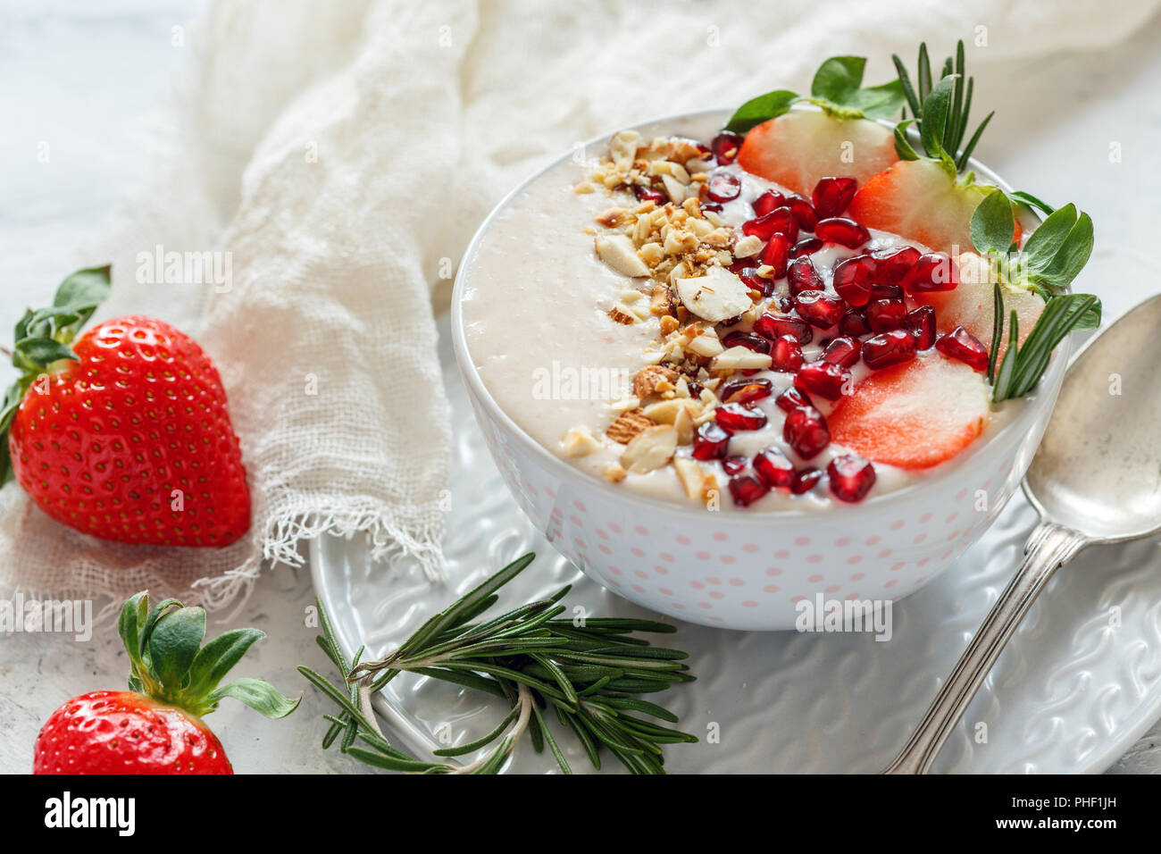 I frullati ciotola con fragole, melograno, dadi. Una sana prima colazione. Foto Stock