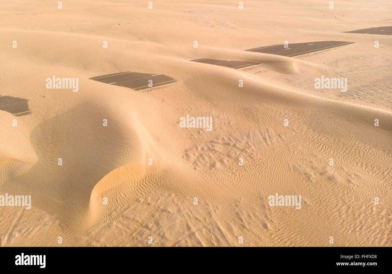 Le dune di sabbia che copre una strada vicino a Dubai Foto Stock